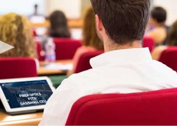 Student in a white shirt sitting in front of a computer in a fiber optic training session